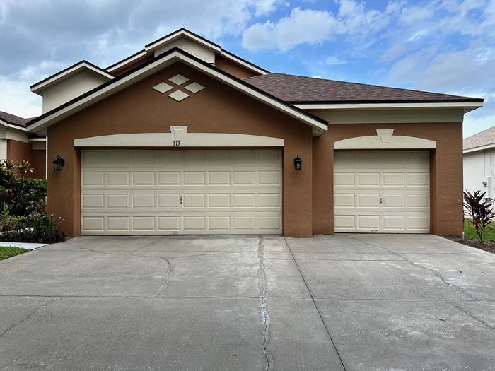 Concrete driveway and garage doors after pressure washing on a single-story stucco home, Central Florida