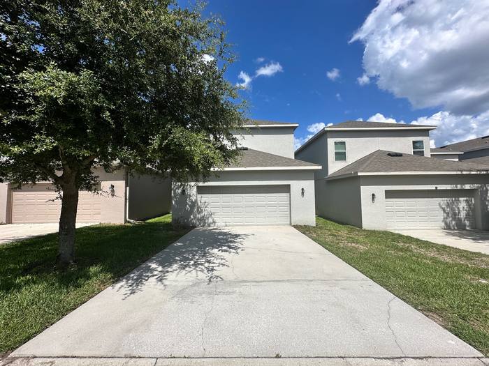 Concrete driveway pressure washing after, bright even finish in front of a two-story stucco home, Central Florida